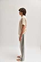 Load image into Gallery viewer, Side image of cream and khaki cotton trousers featuring a wide-leg, relaxed fit with a linen-style drape.
