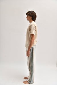 Side image of cream and khaki cotton trousers featuring a wide-leg, relaxed fit with a linen-style drape.